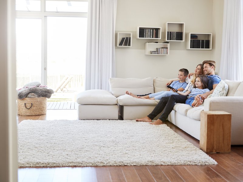relaxing on white couch while your feet are keeping warm by a white area rug from The Carpet Store in Oklahoma City, OK